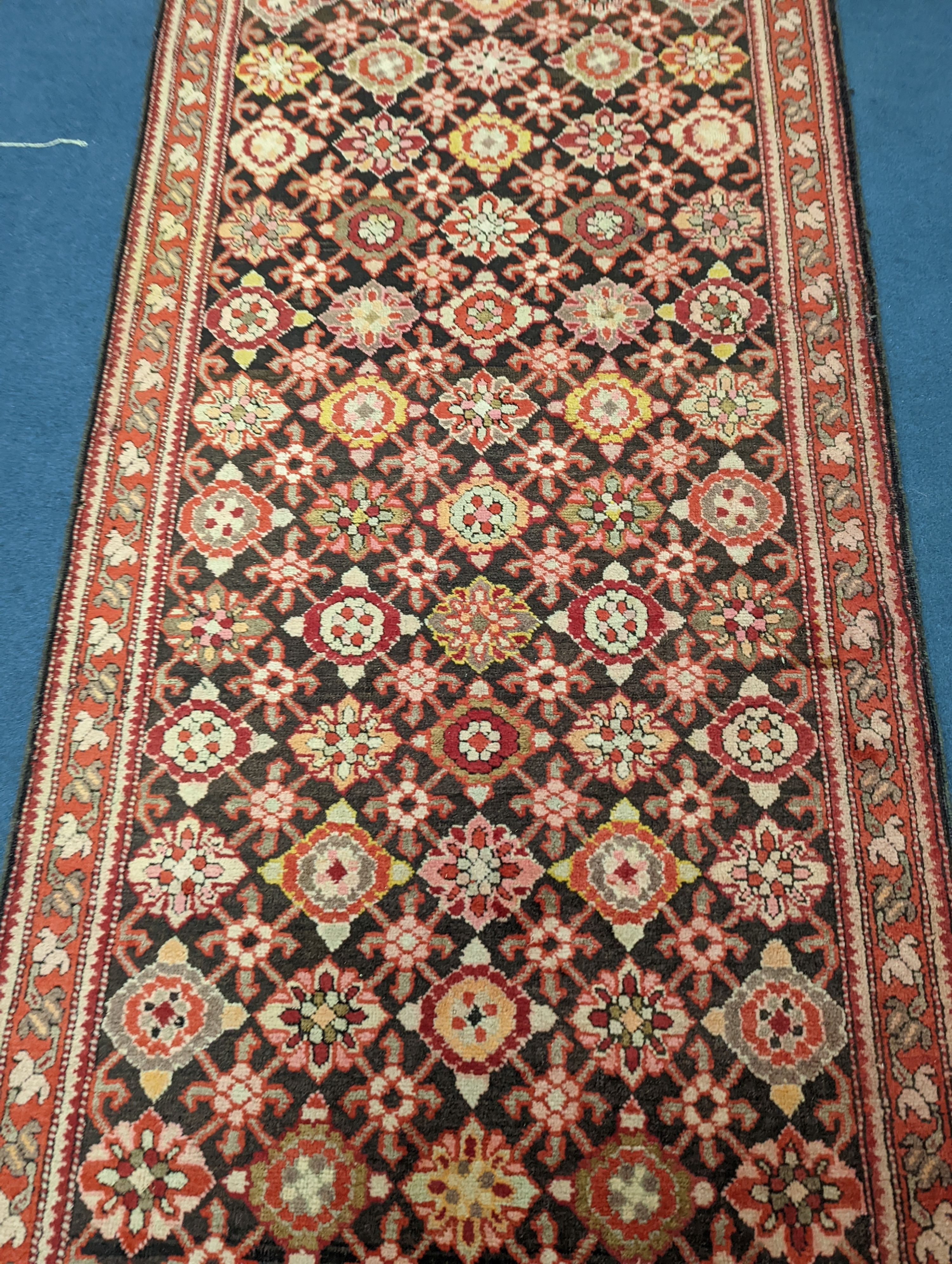 A North West Persian runner woven with rows of floral motifs, 575 x 110cm